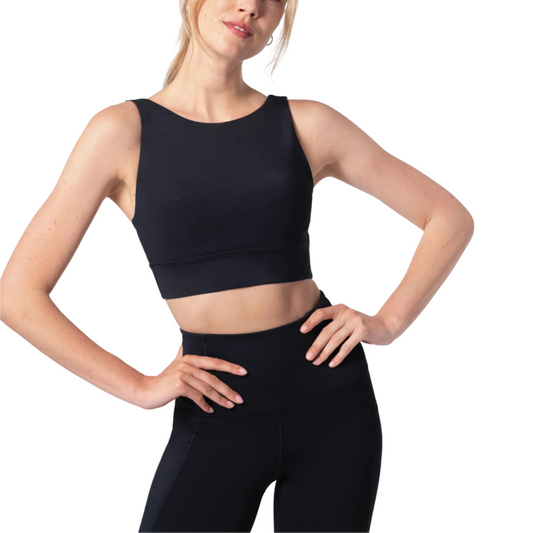 A female model wearing a black longline sports bra with a racerback design.